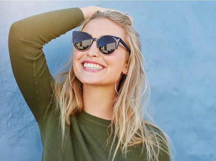 A smiling blonde woman wearing sunglasses